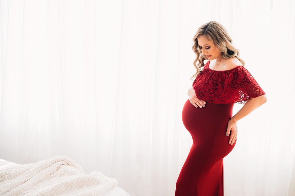 Pregnant Mom in red dress in front of window