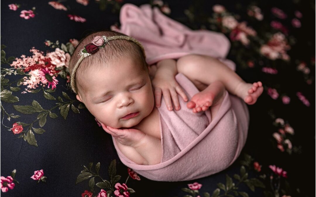 baby girl on navy and pink floral backdrop with pink wrap